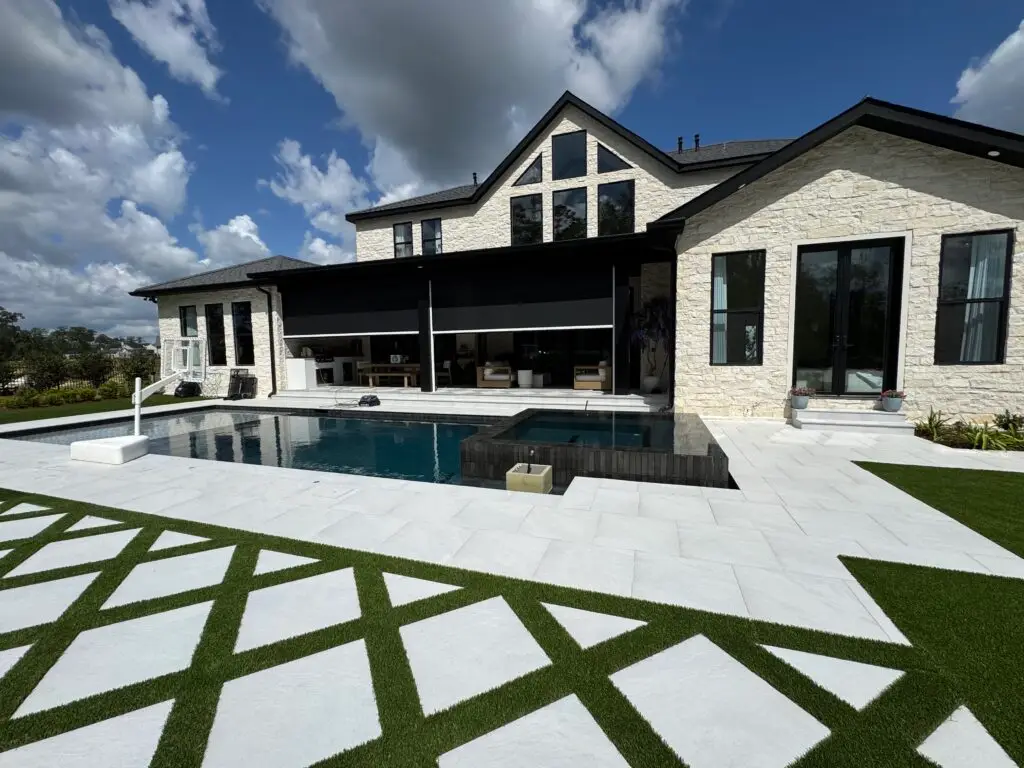 Luxury custom home exterior with pool and motorized patio screens covering the outdoor living area